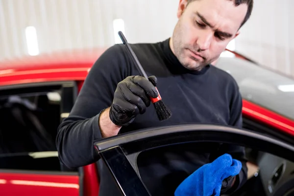 Auto service medewerker reinigt interieur met speciale borstel — Stockfoto