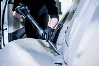 İşçi arabanın içini elektrikli süpürgeyle temizliyor