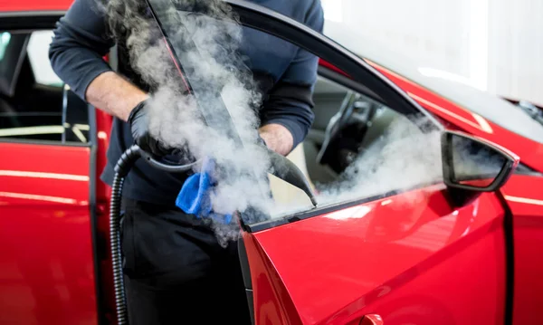 Trabalhador de serviço de carro limpa o interior com aspirador de vapor — Fotografia de Stock