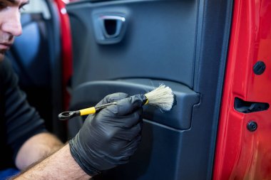 Araba servisi çalışanı iç mekanı özel fırçayla temizliyor