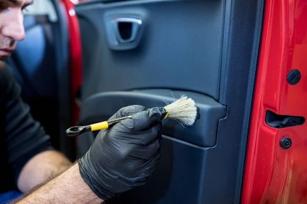 Araba servisi çalışanı iç mekanı özel fırçayla temizliyor