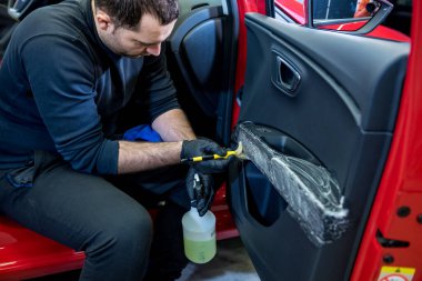 Araba servisi çalışanı iç mekanı özel fırçayla temizliyor