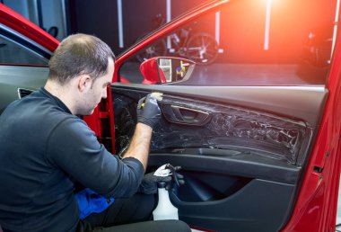 Araba servisi çalışanı iç mekanı özel fırçayla temizliyor