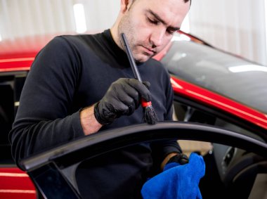 Araba servisi çalışanı iç mekanı özel fırçayla temizliyor