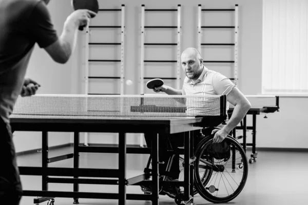 Дорослий інвалідний чоловік у візку грає на настільному тенісі зі своїм тренером — стокове фото