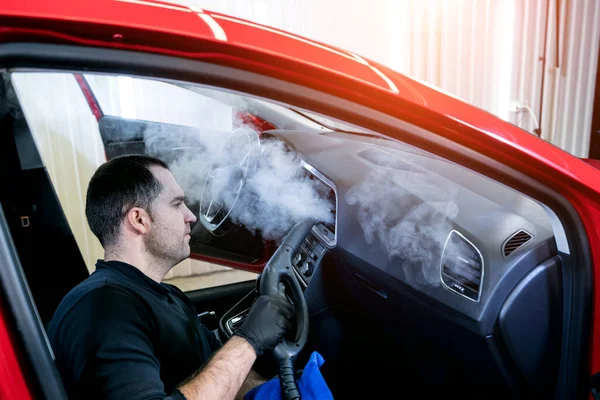 Trabajador de servicio de coches limpia el interior con un limpiador de vapor — Foto de Stock