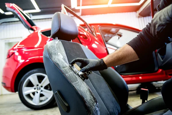 Bilservicearbetare rengör en bilstol med en speciell borste — Stockfoto