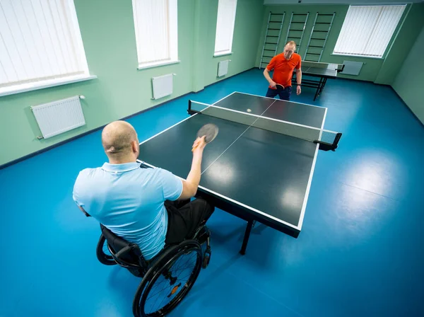 Volwassen gehandicapte man in een rolstoel spelen bij tafeltennis met zijn coach — Stockfoto