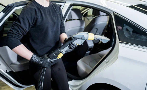 Robotnik czyści wnętrze samochodu odkurzaczem — Zdjęcie stockowe
