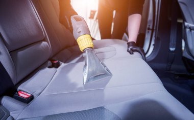 İşçi arabanın içini elektrikli süpürgeyle temizliyor