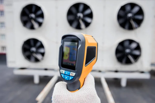 Technician uses a thermal imaging infrared thermometer to check the condensing unit heat exchanger.