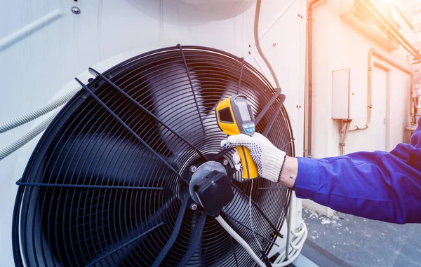 Technicus gebruikt een infrarood thermometer om de condensoreenheid warmtewisselaar te controleren. — Stockfoto