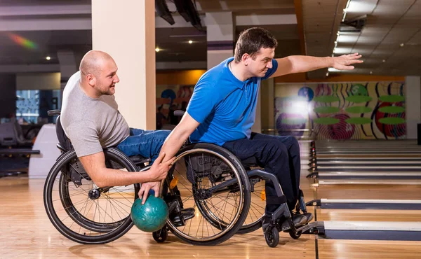 Dos jóvenes discapacitados en sillas de ruedas jugando bolos en el club — Foto de Stock
