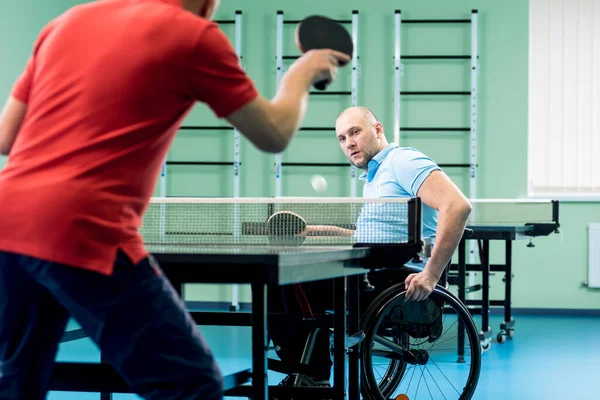 Behinderter Mann im Rollstuhl spielt mit seinem Trainer Tischtennis — Stockfoto
