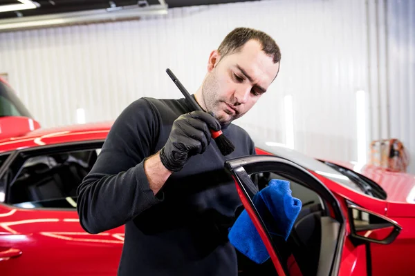 Bilservicearbetare rengör interiör med speciell borste — Stockfoto