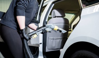 İşçi arabanın içini elektrikli süpürgeyle temizliyor