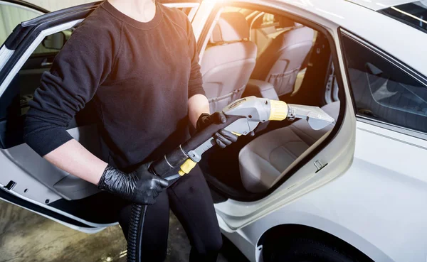 Robotnik czyści wnętrze samochodu odkurzaczem — Zdjęcie stockowe