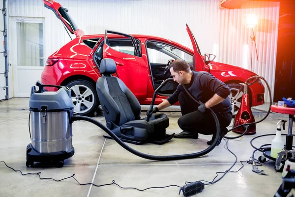 자동차 정비 직원 이 진공청소기로 카시트를 청소하는 모습. — 스톡 사진