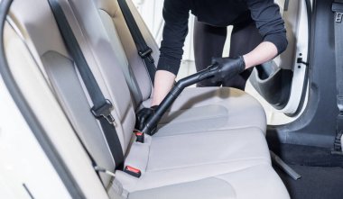 İşçi arabanın içini elektrikli süpürgeyle temizliyor