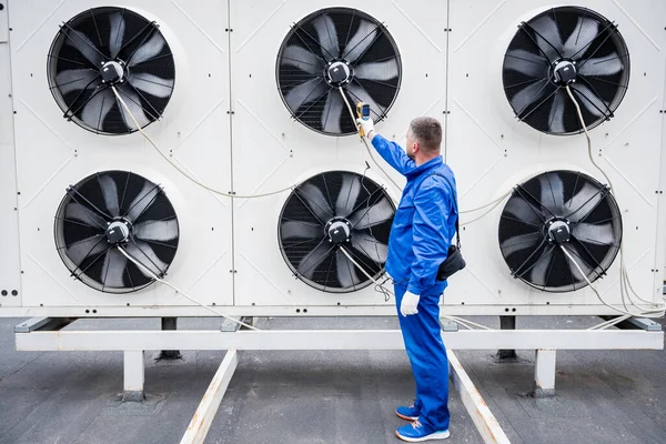 Technicus gebruikt een infrarood thermometer om de condensoreenheid warmtewisselaar te controleren. — Stockfoto