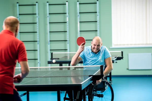 Adult disabled man in a wheelchair play at table tennis with his coach — Stock Photo, Image