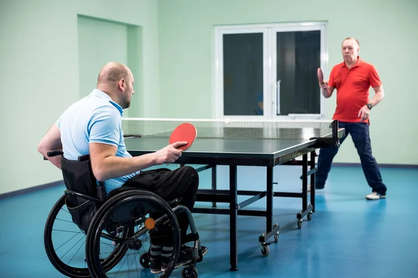 Behinderter Mann im Rollstuhl spielt mit seinem Trainer Tischtennis — Stockfoto