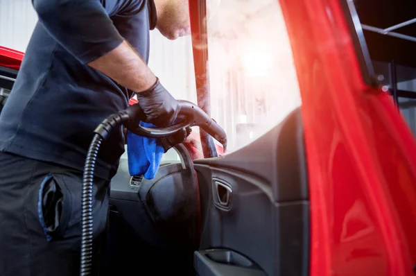 Trabalhador de serviço de carro limpa o interior com aspirador de vapor — Fotografia de Stock