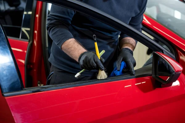 Trabalhador de serviço de carro limpa o interior com escova especial — Fotografia de Stock