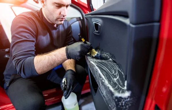 Bilservicearbetare rengör interiör med speciell borste — Stockfoto