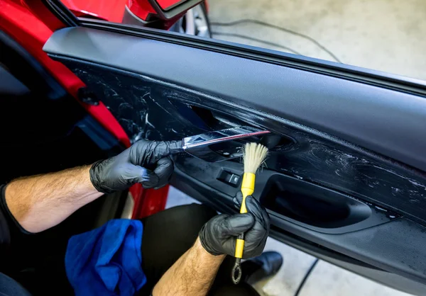 Trabalhador de serviço de carro limpa o interior com escova especial — Fotografia de Stock