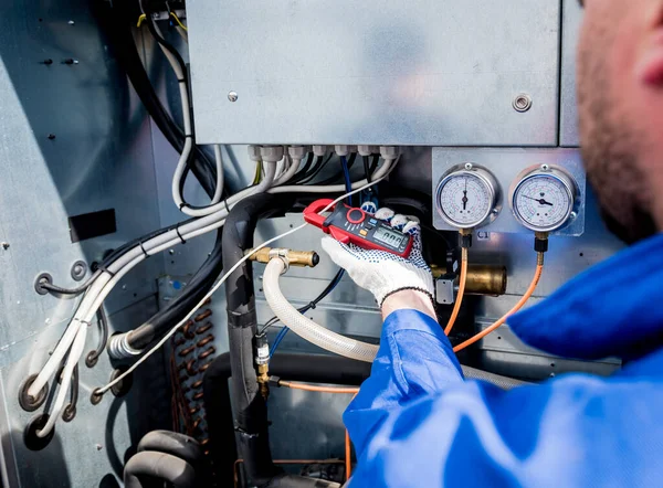 De technicus controleert stroomleidingen van de warmtewisselaar met stroomtang — Stockfoto
