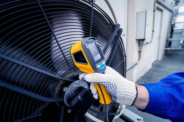 Technicus gebruikt een infrarood thermometer om de condensoreenheid warmtewisselaar te controleren. — Stockfoto