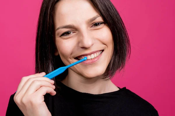 Schöne glückliche junge Frau mit einzelnen Büschel Zahnbürste auf leerem rosa Hintergrund — Stockfoto