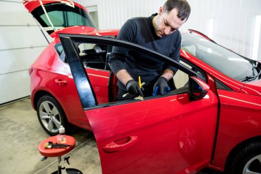 Araba servisi çalışanı iç mekanı özel fırçayla temizliyor