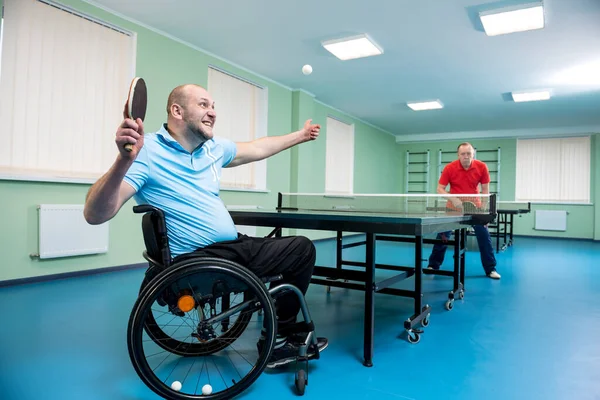 Volwassen gehandicapte man in een rolstoel spelen bij tafeltennis met zijn coach — Stockfoto