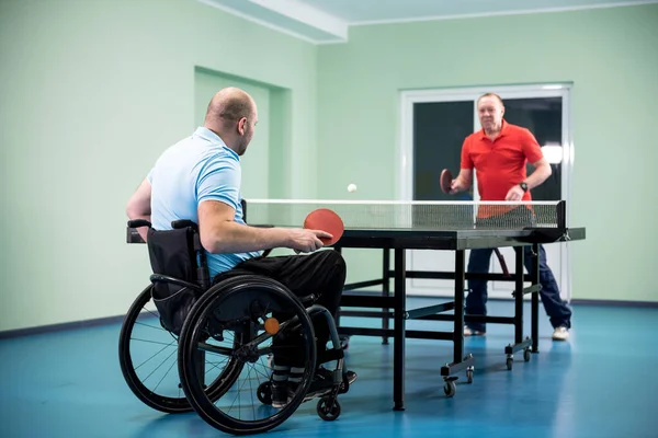 Adulto discapacitado en silla de ruedas jugar al tenis de mesa con su entrenador —  Fotos de Stock