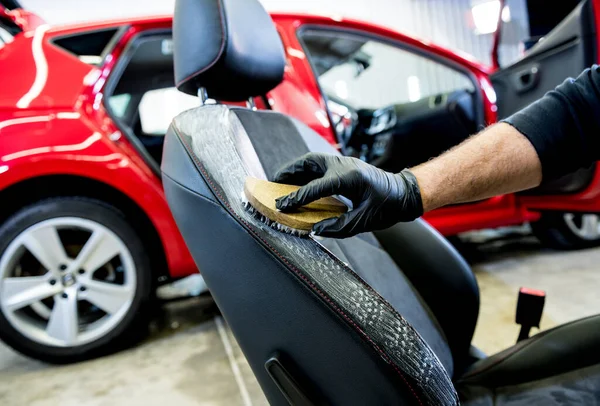 Trabajador de servicio de coches limpia una silla de coche con un cepillo especial — Foto de Stock