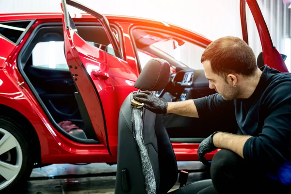 Car service worker czyści fotelik specjalną szczotką — Zdjęcie stockowe