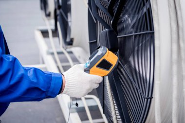 Technician uses a thermal imaging infrared thermometer to check the condensing unit heat exchanger. clipart