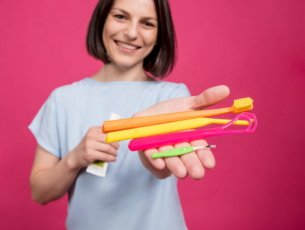 Beautiful young woman uses an oral care kit consisting of a tongue scraper, single tufted and interdental brush