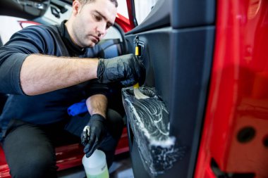 Araba servisi çalışanı iç mekanı özel fırçayla temizliyor