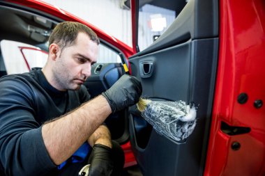 Araba servisi çalışanı iç mekanı özel fırçayla temizliyor