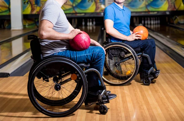 Två unga funktionshindrade män i rullstol spelar bowling i klubben — Stockfoto