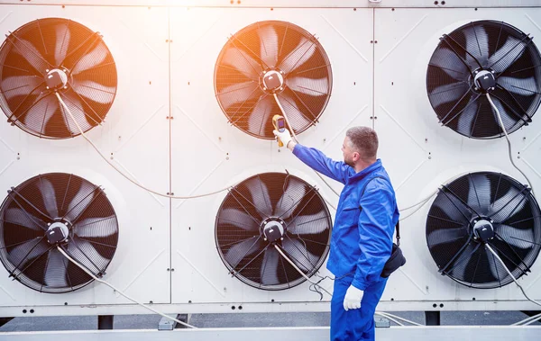 Technicus gebruikt een infrarood thermometer om de condensoreenheid warmtewisselaar te controleren. — Stockfoto