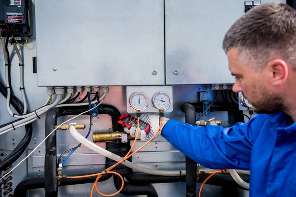 Der Techniker überprüft die Stromleitungen des Wärmetauschers mit Stromzangen — Stockfoto