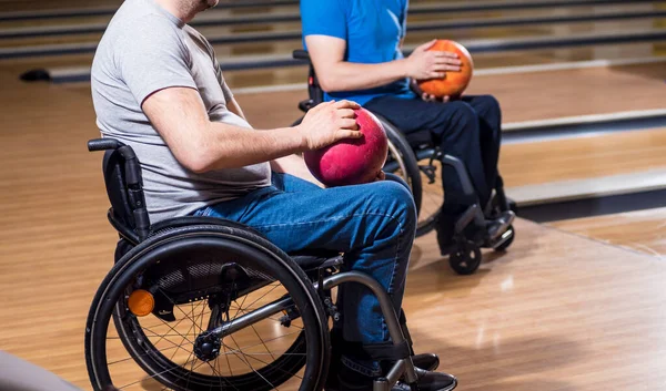 Два молодых инвалида в инвалидных колясках играют в боулинг в клубе — стоковое фото