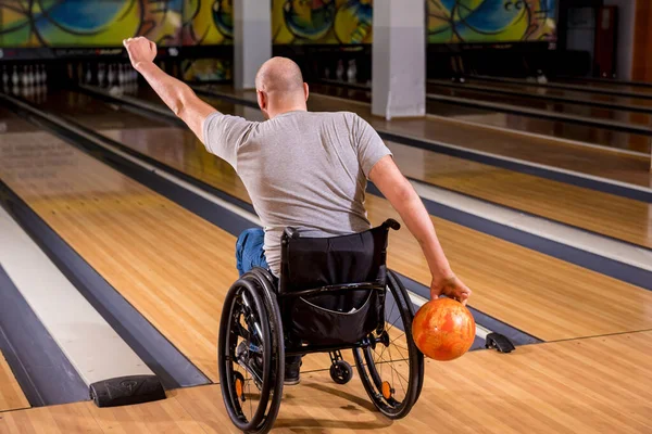 Joven discapacitado en silla de ruedas jugando bolos en el club —  Fotos de Stock