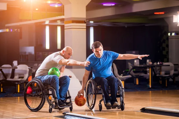 Due giovani disabili in sedia a rotelle che giocano a bowling nel club — Foto Stock