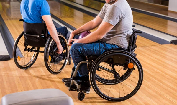 Twee jonge gehandicapte mannen in rolstoelen die bowlen in de club — Stockfoto