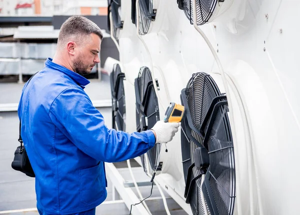 Technicus gebruikt een infrarood thermometer om de condensoreenheid warmtewisselaar te controleren. — Stockfoto